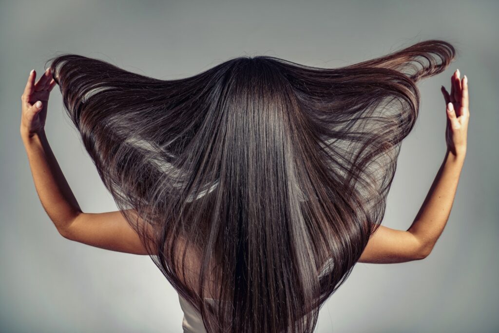 Back view of a brunette woman with a long straight hair.